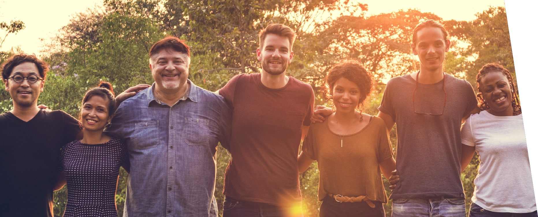 Group of people standing outside together during a sunset. 