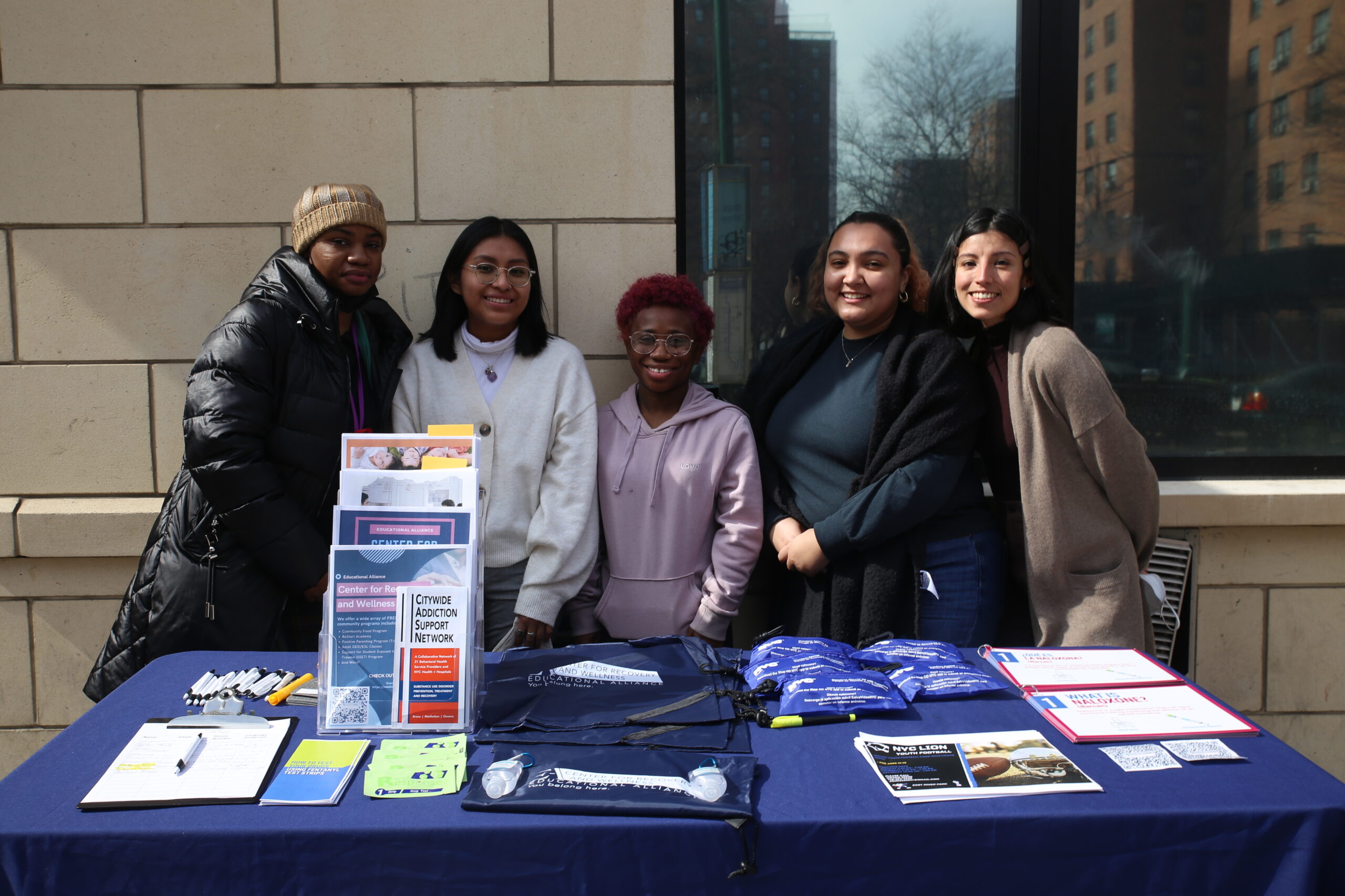 group of people standing together at a table outside.