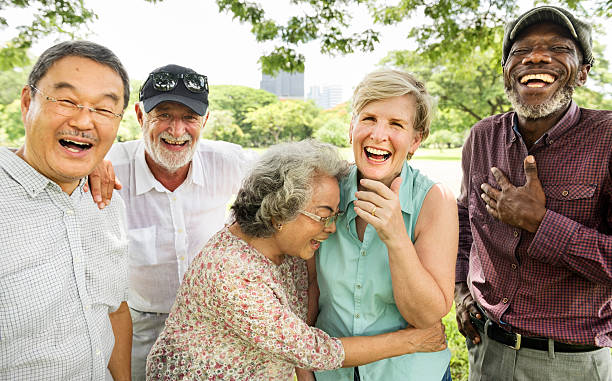 Group of two older men and two older women celebrating and hugging all together outside